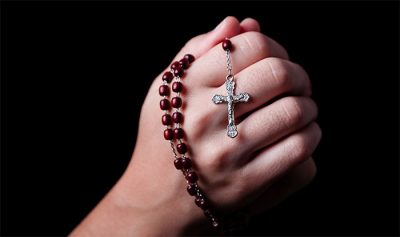 women hands praying rosary